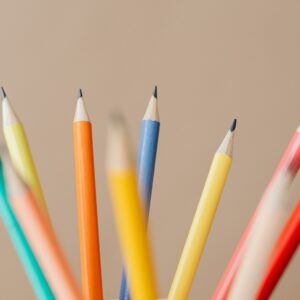 Vibrant close-up of sharpened colored pencils against a beige background, ideal for creative concepts.